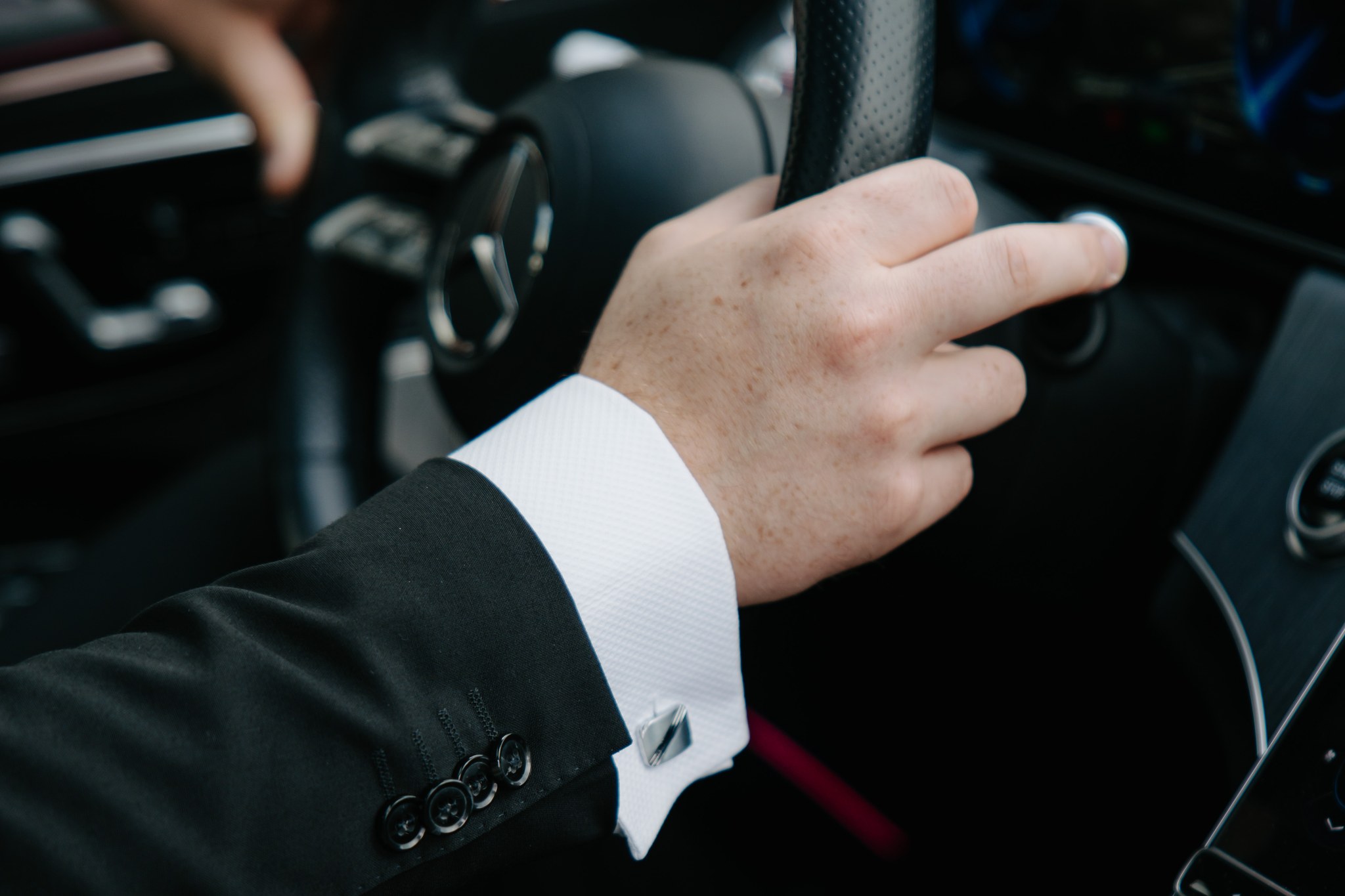 Close-up of a LuxLimo chauffeur's hands on the steering wheel, white shirt cuff and cufflink