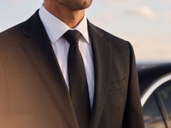 Close-up of a LuxLimo chauffeur in a dark suit, white shirt and black tie