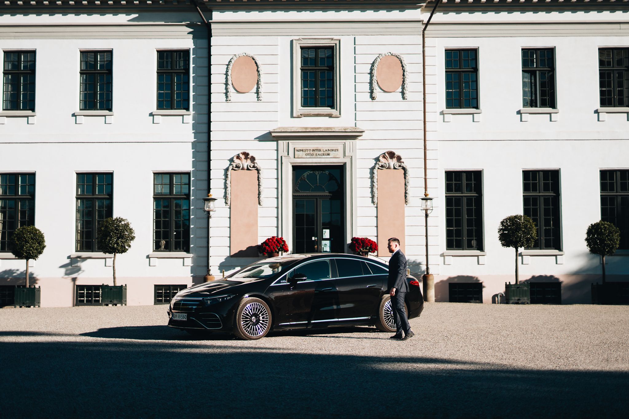 LuxLimo chauffeur standing at the Mercedes-Benz EQS in front of a Danish manor house