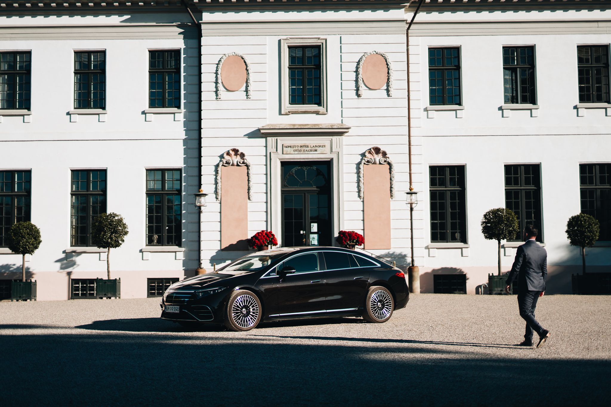 LuxLimo chauffeur walking to the Mercedes-Benz EQS in the courtyard of a Danish manor house