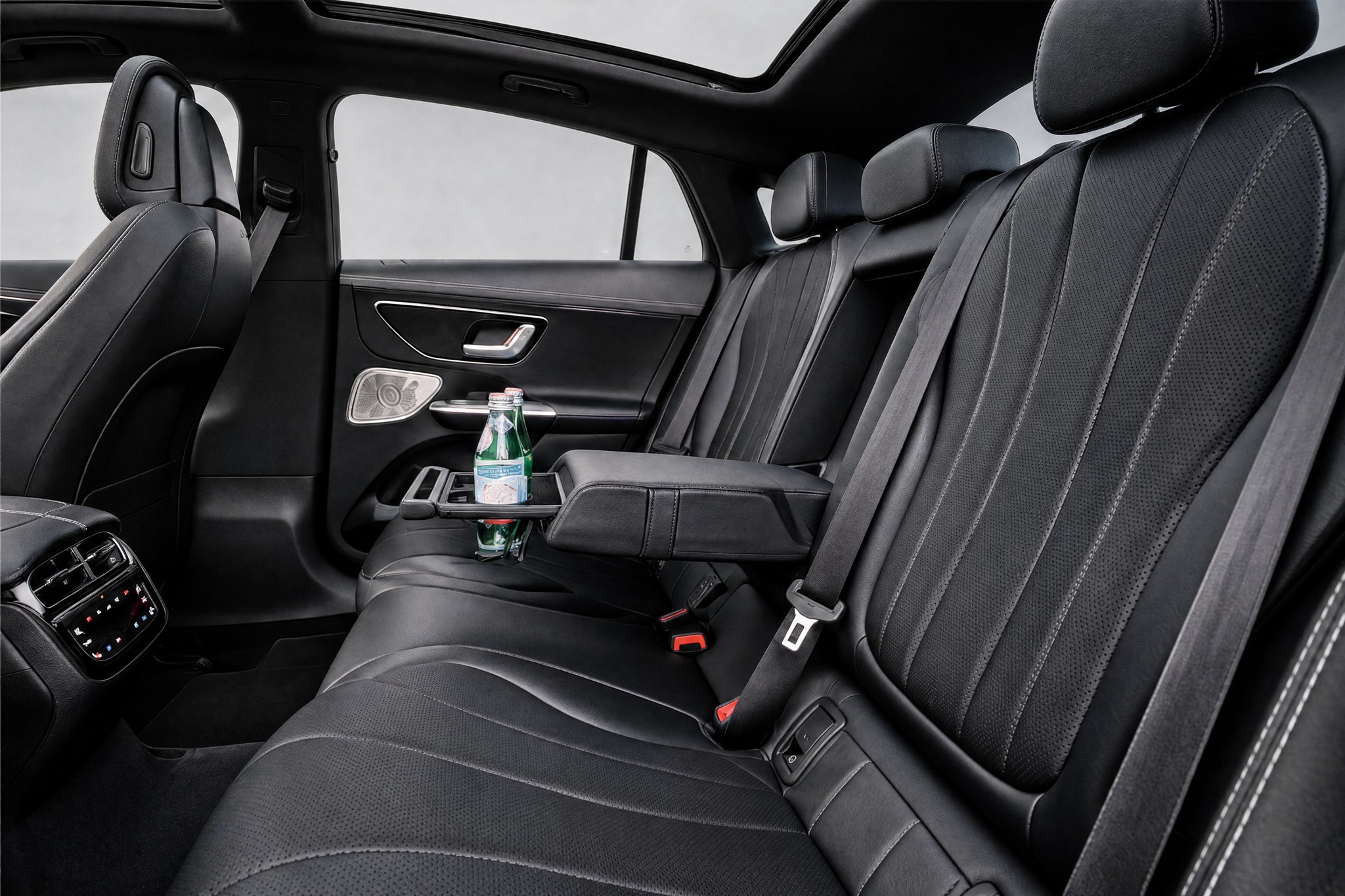 Rear seats of the Mercedes-Benz EQE, the LuxLimo Business, seen from the side, with the climate controls and still water in the centre