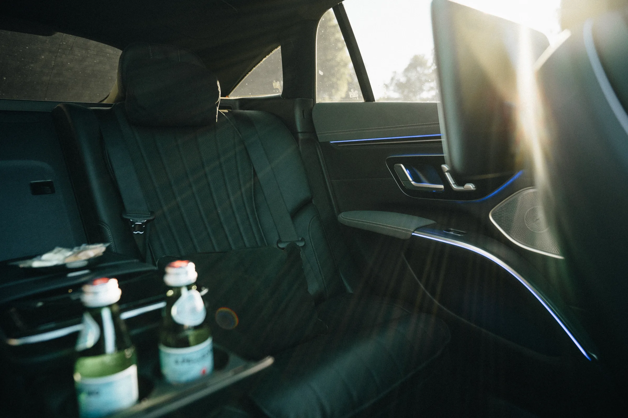 Rear seat of a LuxLimo chauffeur car in Copenhagen in afternoon light, water bottles in the door, ready for a chauffeur for a day